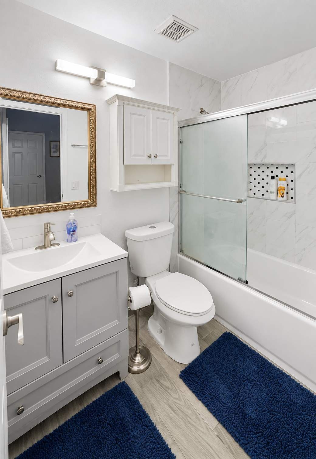 Une salle de bain comprenant des toilettes, un lavabo, un meuble-lavabo et un espace douche.
