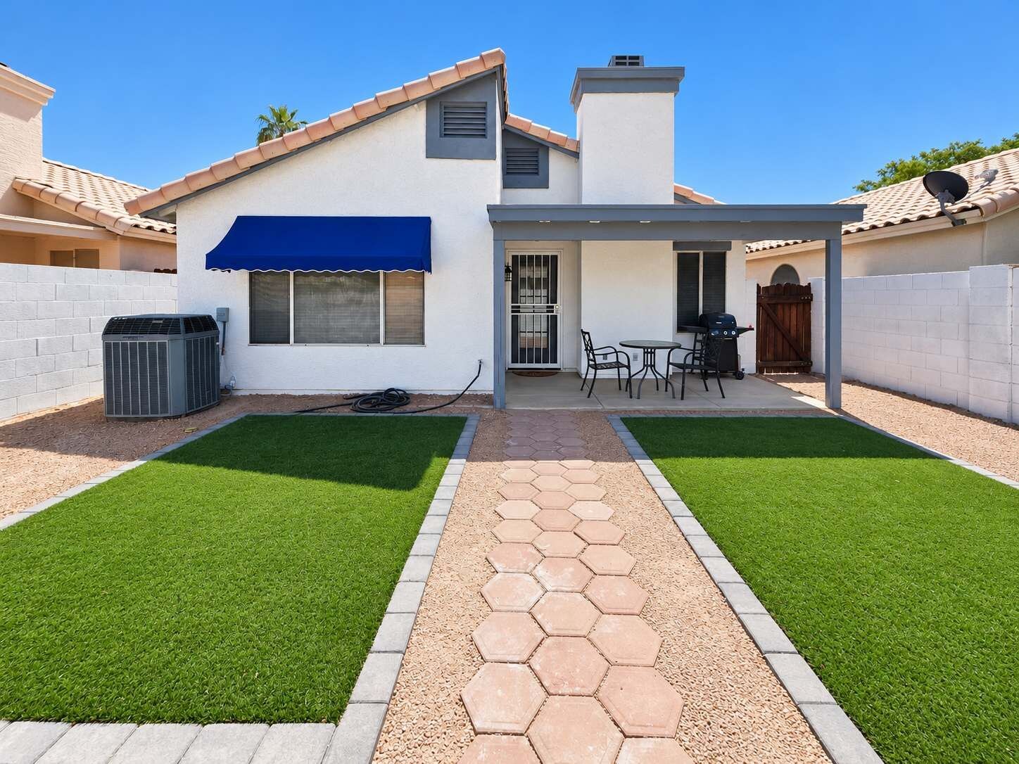 Il s’agit d’une propriété résidentielle dotée d’une terrasse, d’un espace salon extérieur et d’une pelouse bien entretenue.
