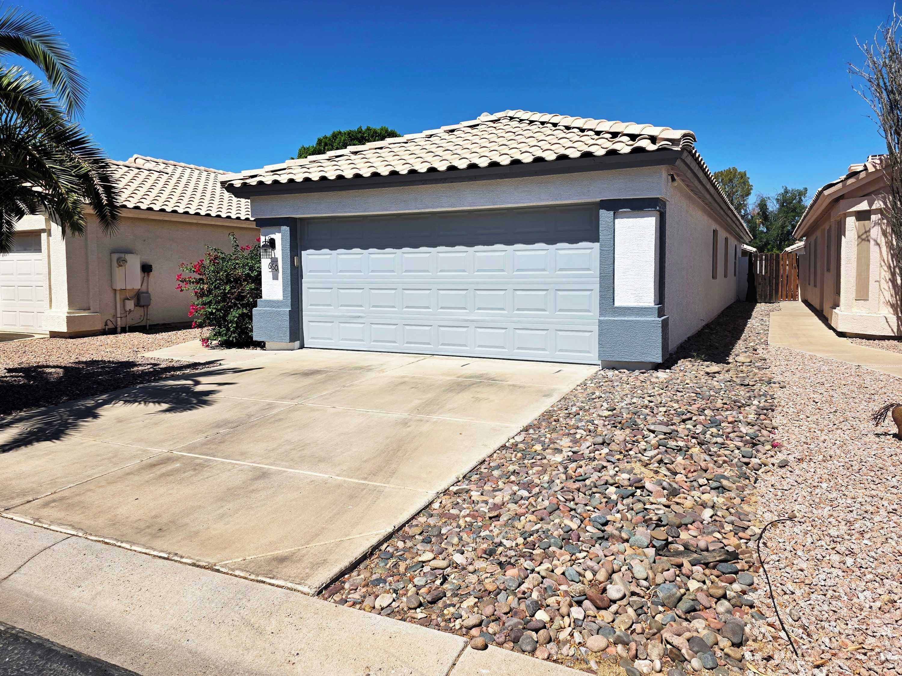 A residential property with a garage, a driveway, and a gravel pathway.