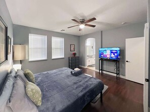 A bedroom with a bed, a ceiling fan, a TV, and a wardrobe.