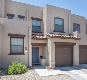 A two-story residential building with a flat roof, a front door, and a garage.