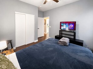 Ein Schlafzimmer mit einem Bett, einem Fernseher und einer Tür.