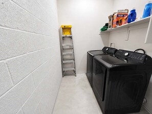 A laundry room with a washing machine, a drying rack, and shelves with cleaning supplies. - Pet-Friendly 3BR | Community Pool | Near ASU (Tempe)