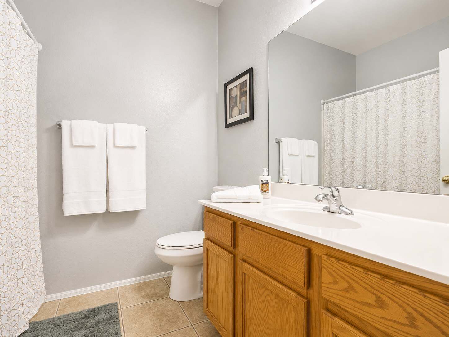 A bathroom with a toilet, a sink, and a mirror. There are two towels hanging on the wall.