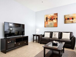 A modern living room with a flat-screen TV, a dark brown leather sofa, a coffee table, and abstract wall art. - Pet-Friendly 3BR | Community Pool | Near ASU (Tempe)
