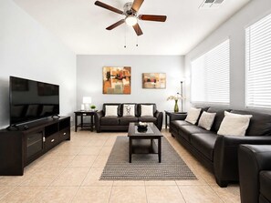 A modern living room with a flat-screen TV, a ceiling fan, two sofas, a coffee table, and artwork on the walls. - Pet-Friendly 3BR | Community Pool | Near ASU (Tempe)