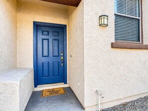 A blue door with a doormat that reads 'Welcome to Home.'