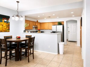 A modern kitchen with wooden cabinets, a central island, and a dining area with a table and chairs. - Pet-Friendly 3BR | Community Pool | Near ASU (Tempe)
