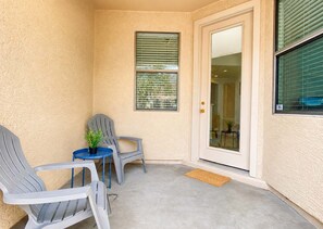 A corner of a room with a door, two chairs, a small table, and a potted plant.