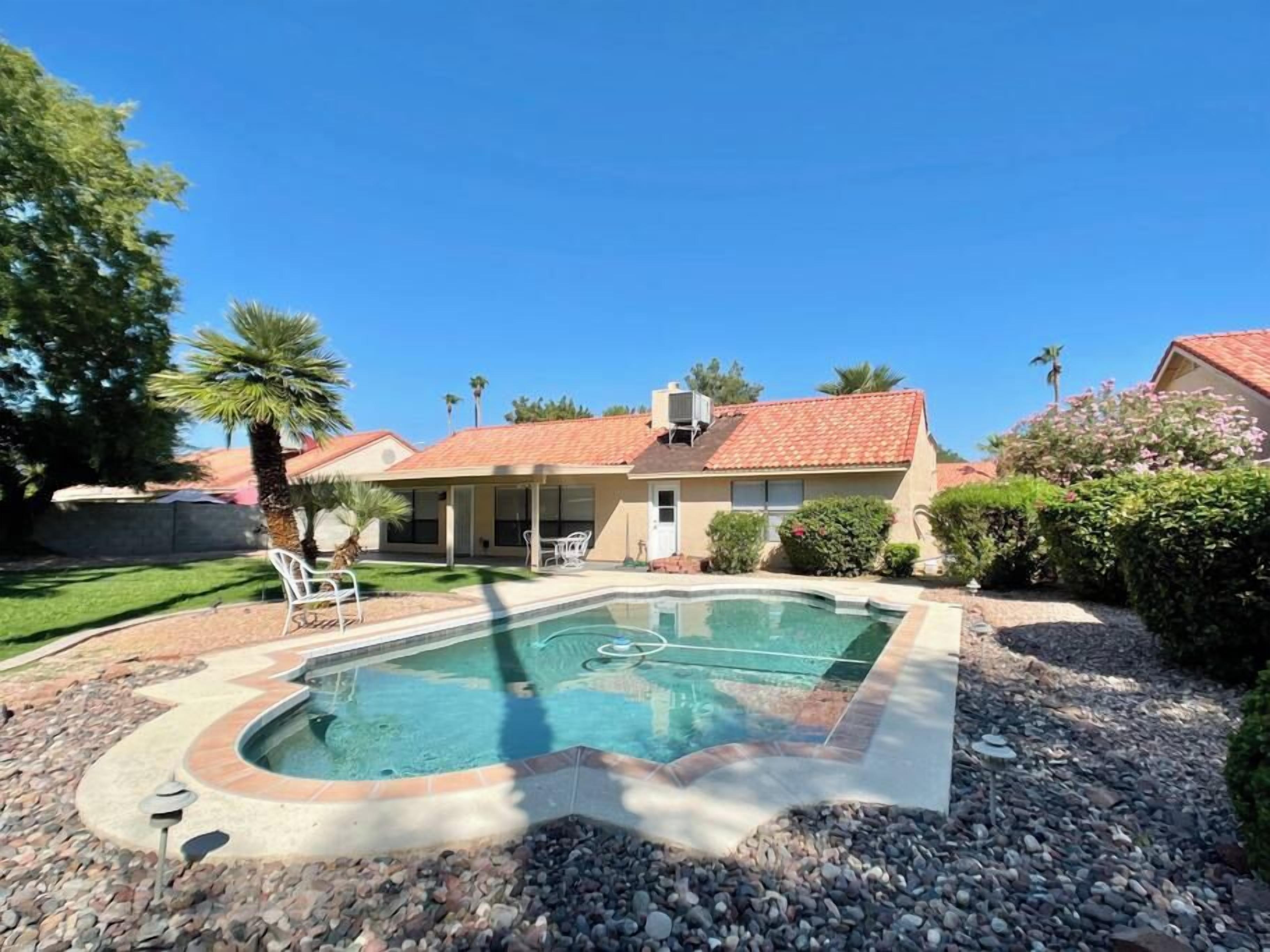 Une propriété résidentielle dotée d’une piscine, d’un patio couvert et d’un jardin bien entretenu.