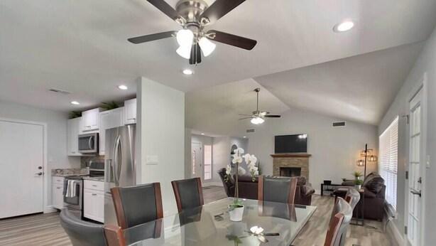 A modern kitchen with white cabinets, stainless steel appliances, and a dining area with a glass table and leather chairs. - Pristine! Single-Story Home with Pool in Chandler (Chandler)