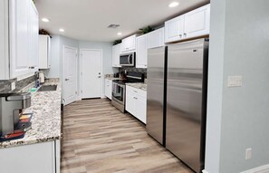 A kitchen with white cabinets, a stainless steel refrigerator, a microwave, and a coffee maker. - Chandler Pool Home | King Bed | Pet Friendly (Chandler)