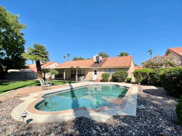A residential property with a swimming pool, a covered patio, and a well-maintained garden.