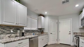 A modern kitchen with white cabinets, a granite countertop, stainless steel appliances, and a patterned backsplash. - Pristine! Single-Story Home with Pool in Chandler (Chandler)