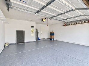 Un vaste espace intérieur doté d’un sol en béton, d’une porte, d’un distributeur d’eau et d’un système de ventilation.