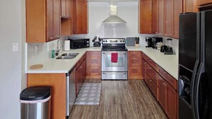 Una cocina compacta con armarios de madera, un lavamanos de acero inoxidable, un microondas, una estufa y un refrigerador.