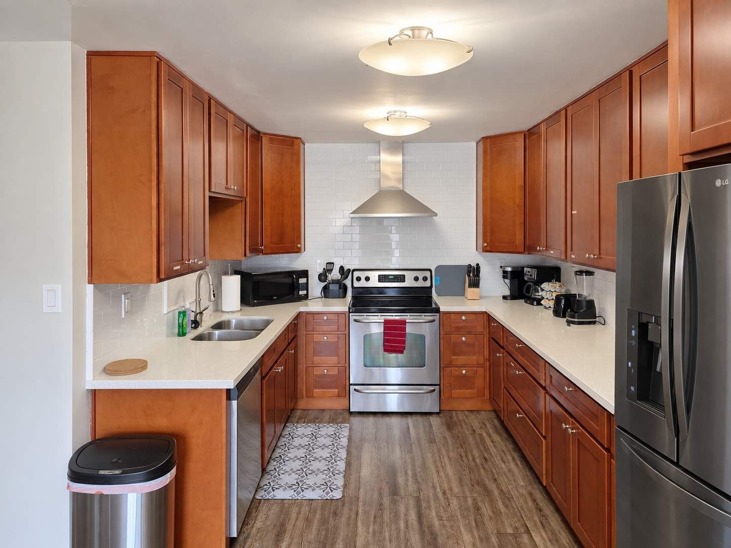 A compact kitchen with wooden cabinets, stainless steel appliances, and a tiled backsplash.