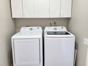 Un espace buanderie avec deux machines à laver blanches et un meuble de rangement au-dessus.