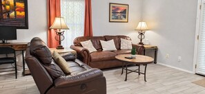 A living room with a brown leather sofa, a wooden coffee table, and two lamps.