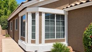 A residential building with a corner bay window, a tiled roof, and a stucco exterior.