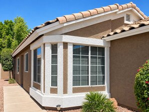 A residential building with a corner bay window, a tiled roof, and a stucco exterior.