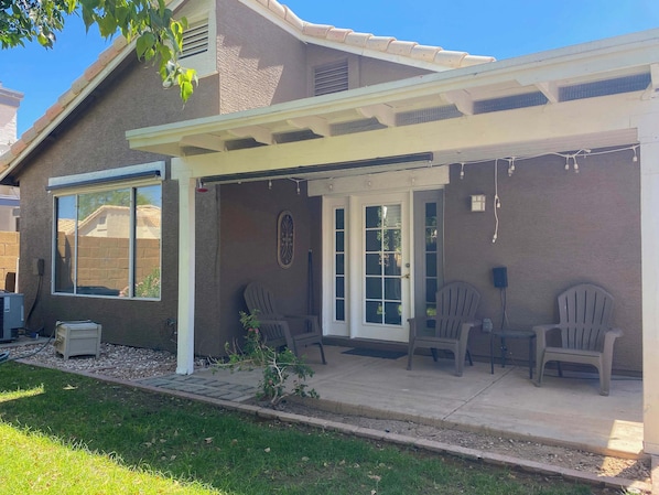 A house with a covered patio, a door with glass panels, and two Adirondack chairs.
