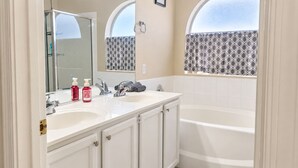 A bathroom with two sinks, a bathtub, and a shower.