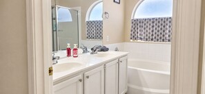 A bathroom with two sinks, a bathtub, and a shower.