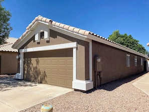 A residential building with a garage, a covered porch, and a gravel driveway.