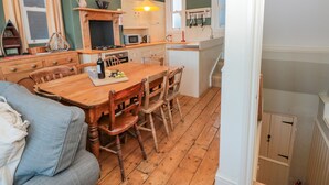 Een gezellige keuken met houten meubels, een eettafel en een vast kookeiland met spoelbak.