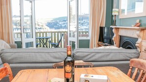 Een houten tafel met een fles wijn, druiven, kaas en crackers op een snijplank.