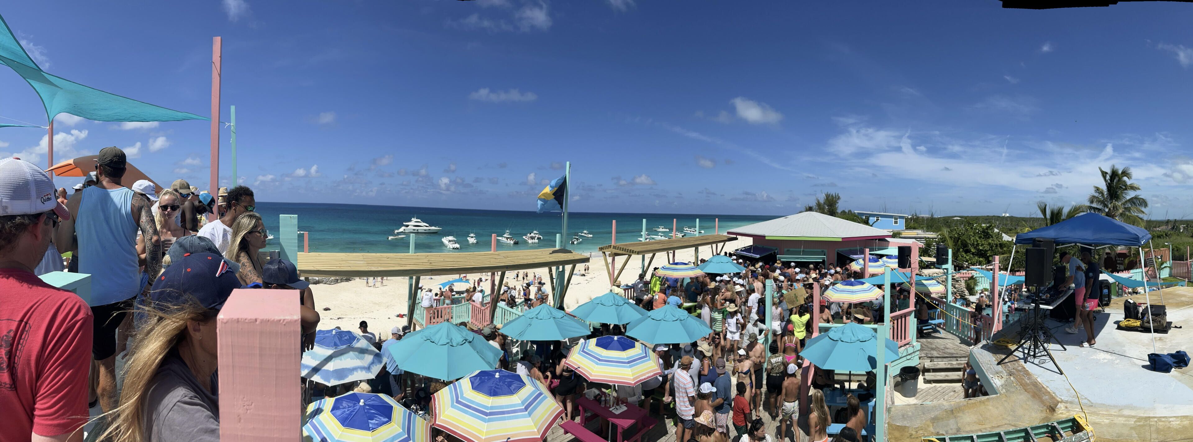 Een druk strand met veel parasols en mensen.