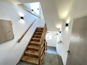 A wooden staircase with a handrail, white walls, and a window at the top. - Apartment with a veranda, free parking, child-friendly, near Schönbrunn, garden (Wien)