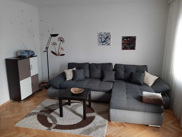 A modern living room with a grey sectional sofa, a small black coffee table, and a white cabinet.