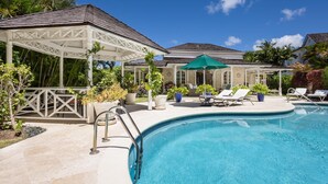A pool area with lounge chairs, a covered seating area, and a pergola.