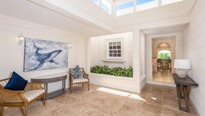 A spacious indoor area with a high ceiling, a large window, and a view into another room.