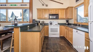 A spacious kitchen with wooden cabinets, a large island, a stove, and a dishwasher. - Cozy Big Horn Home Walking Distance to Big Sky Resort | Ski-In/Out | Fireplace (Big Sky)