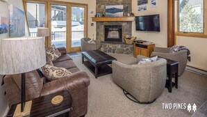 A cozy living room with a stone fireplace, leather sofas, and a television. - Cozy Big Horn Home Walking Distance to Big Sky Resort | Ski-In/Out | Fireplace (Big Sky)