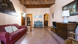 A living room with a red sofa, a blue bench, a wooden cabinet, and a painting on the wall. - Ruote Apartment first (Firenze)