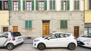 A row of parked cars in front of a building with a stone facade and green shutters. - Ruote Apartment first (Firenze)