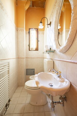Un baño con un lavamanos blanco, inodoro y espejo con un marco decorativo.