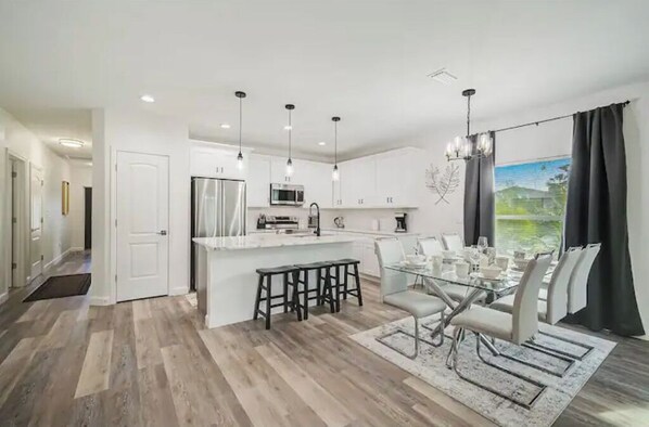 A modern kitchen with white cabinets, a central island, and pendant lighting.