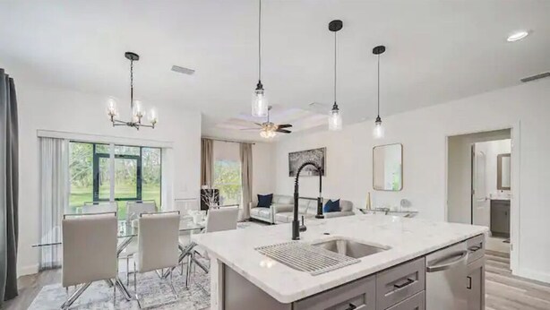 A modern kitchen with a central island, stainless steel appliances, and pendant lighting.