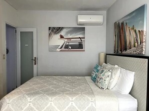 A bedroom with a bed, a painting of a boat on the wall, and a surfboard collection. - Mares Guesthouse (Aguada)