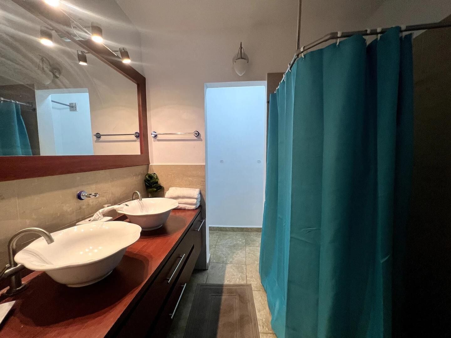 Ein Badezimmer mit zwei Waschbecken, einem Spiegel und einer Duschvorhang.