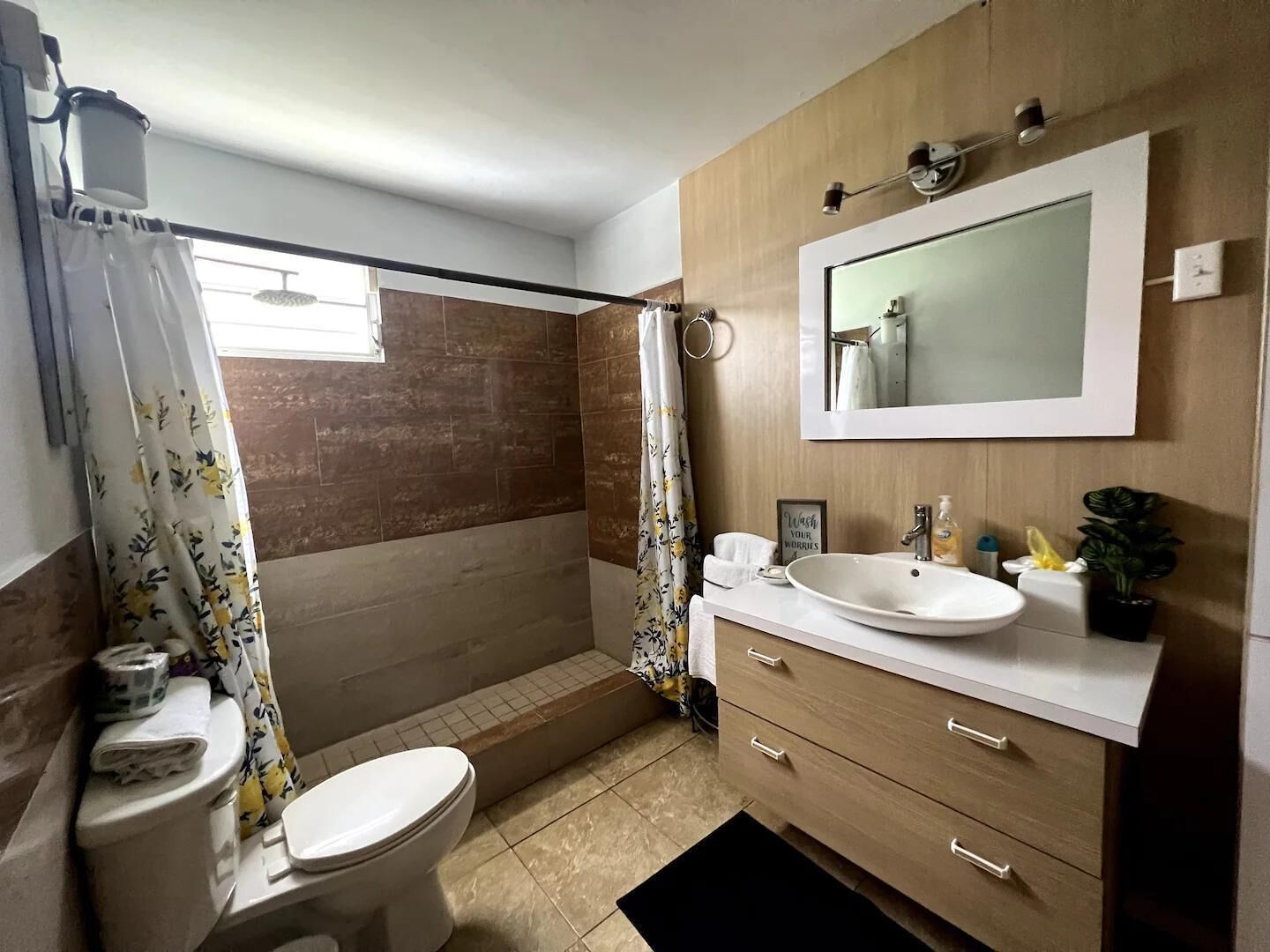 Un baño con inodoro, lavamanos, espejo y cortina de ducha.