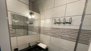 Ett modernt badrum med en svart tvättställ, en spegel, en handduk och en dusch.