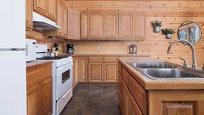 Una cocina con armarios de madera, una estufa, un fregadero y un espejo.