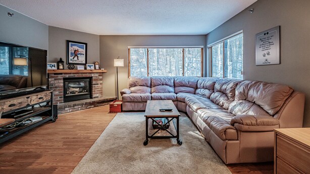 A living room with a fireplace, a large leather sofa, a coffee table, and a TV.