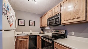 A kitchen with wooden cabinets, a microwave, an oven, and a dishwasher.